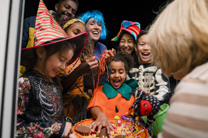 group of children in halloween costumes taking candy from a bowl