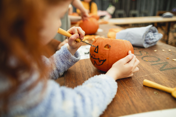 girl carving a small pumpkin following some pumpkin picking
